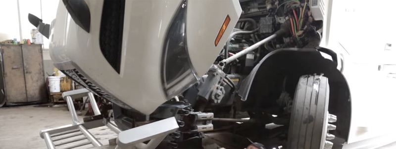 White semi truck with cab tilted forward for front end repair
